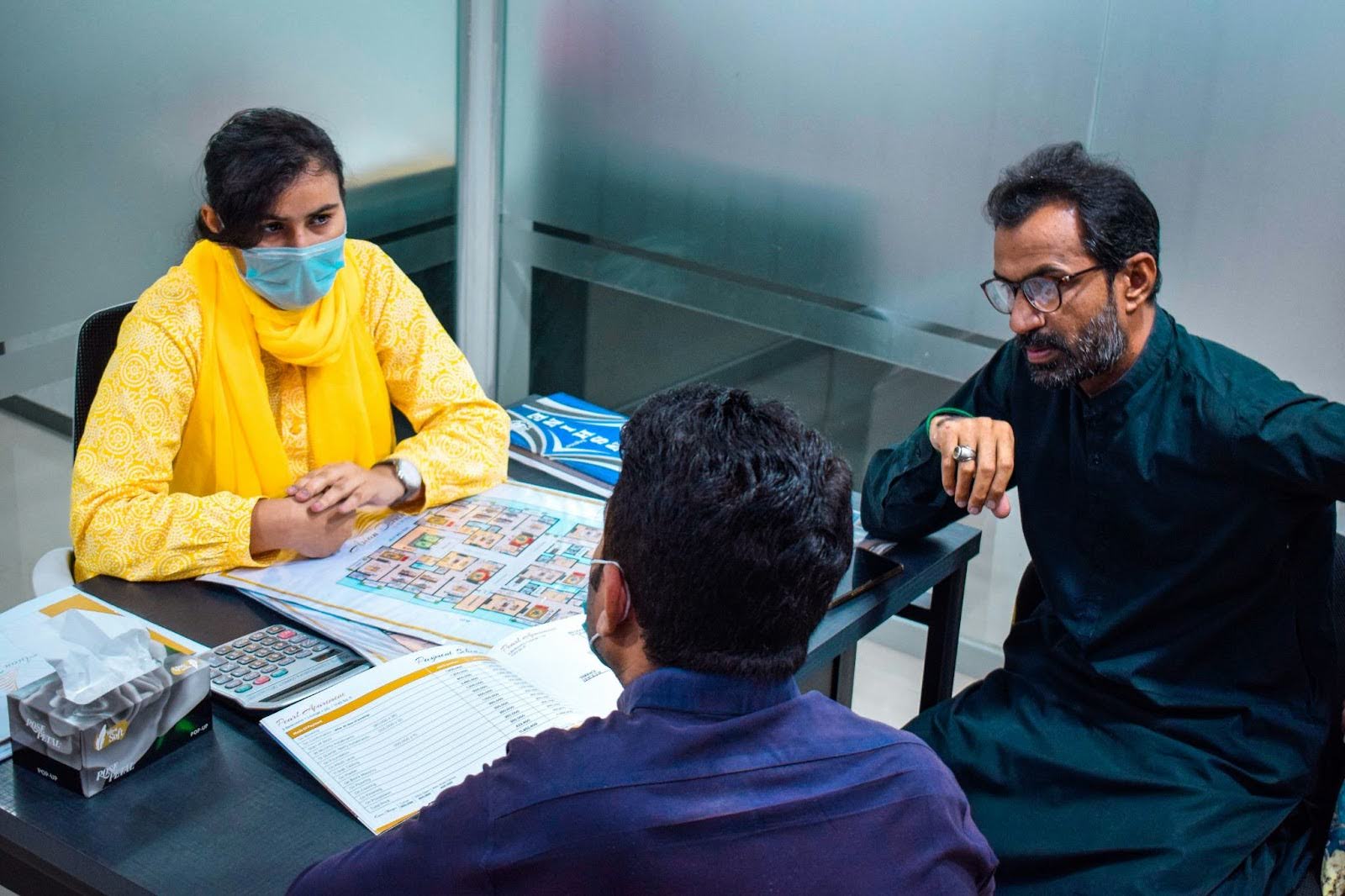 three people at desk with papers